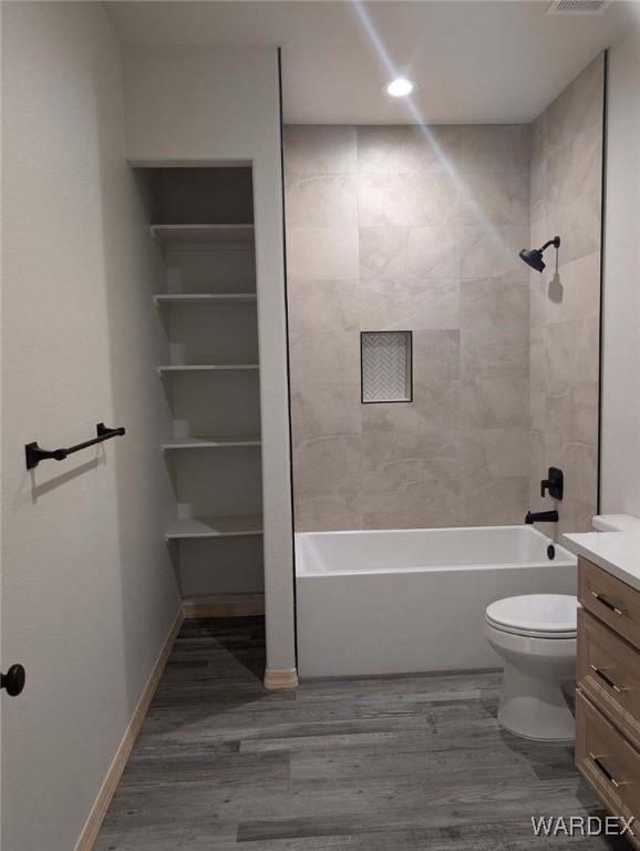 full bathroom featuring shower / bath combination, baseboards, toilet, wood finished floors, and vanity