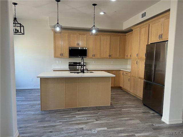 kitchen with an island with sink, stainless steel appliances, light countertops, light brown cabinets, and a sink