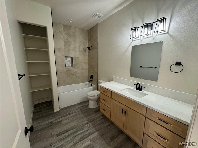 full bathroom featuring visible vents, toilet, wood finished floors, vanity, and washtub / shower combination