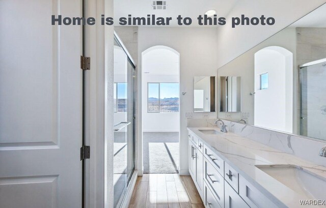 full bathroom featuring double vanity, a sink, visible vents, and a shower with door