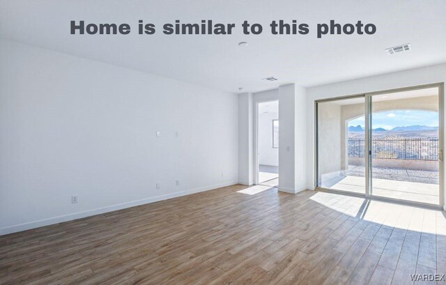 empty room featuring baseboards, visible vents, and wood finished floors