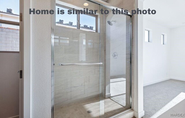 bathroom with plenty of natural light, a shower stall, and baseboards