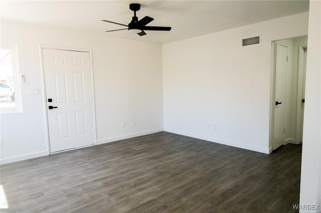 spare room with dark wood-style floors, baseboards, ceiling fan, and visible vents