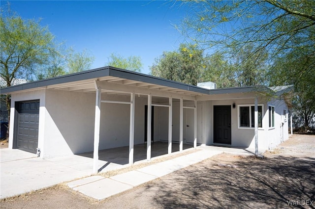 back of property featuring stucco siding, an attached garage, an attached carport, and concrete driveway