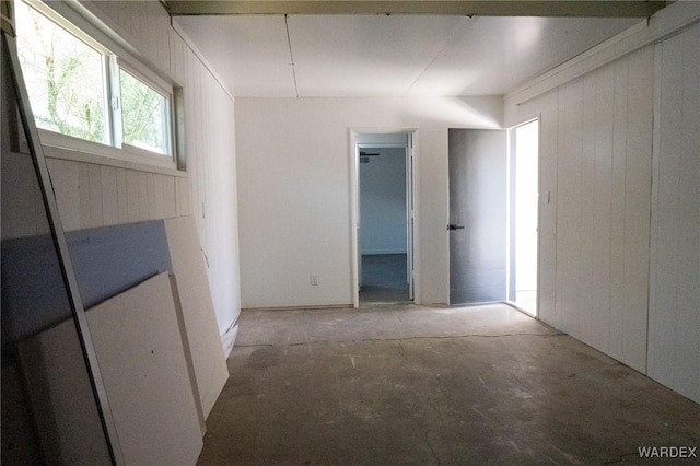 unfurnished room featuring wood walls and unfinished concrete floors