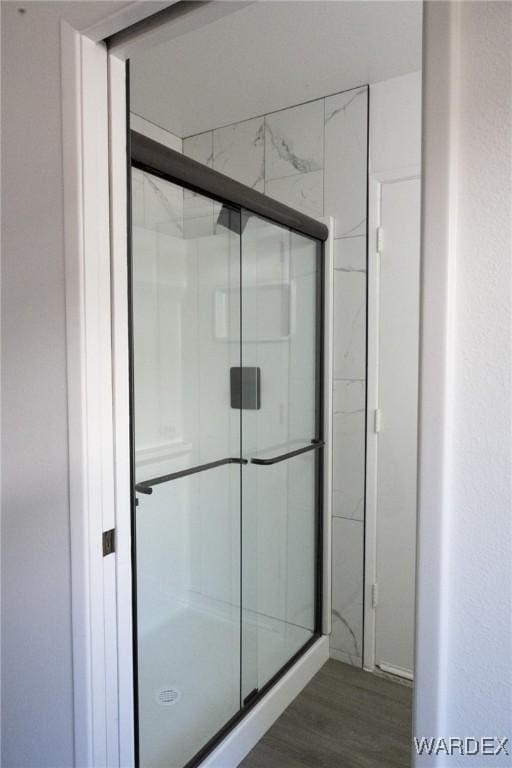 full bath featuring a shower stall and wood finished floors