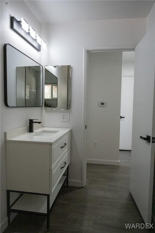 bathroom with baseboards, wood finished floors, and vanity