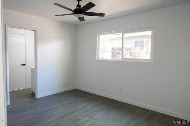 spare room with baseboards, a ceiling fan, and dark wood-style floors