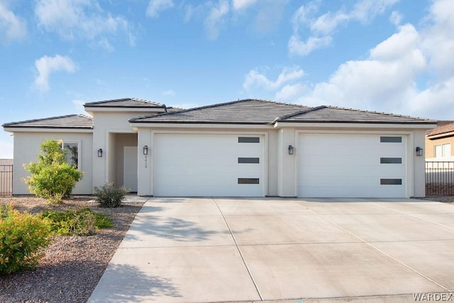 prairie-style house featuring a garage, a tile roof, driveway, and stucco siding