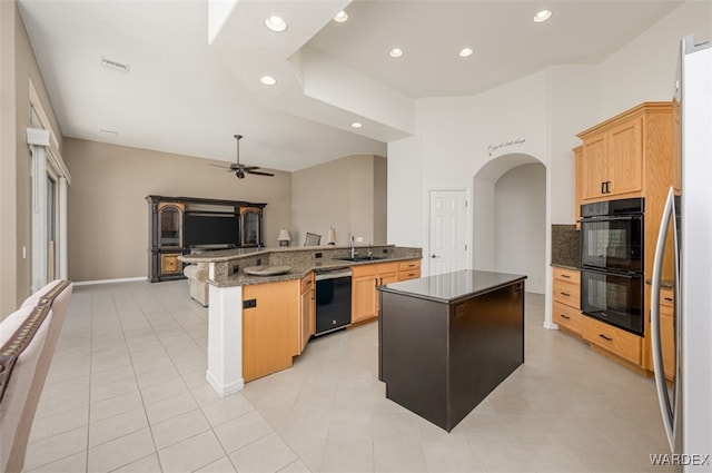 kitchen with a ceiling fan, open floor plan, a kitchen island, a peninsula, and black appliances