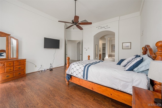 bedroom featuring visible vents, arched walkways, a ceiling fan, ensuite bath, and wood finished floors