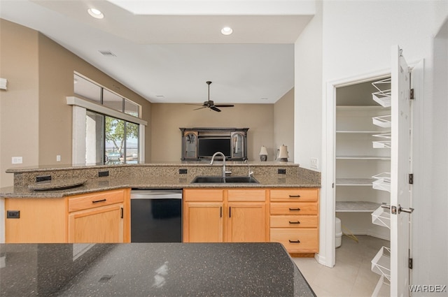 kitchen featuring dark stone countertops, light brown cabinets, dishwasher, and a sink