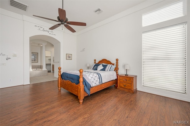 bedroom featuring arched walkways, visible vents, ceiling fan, and wood finished floors