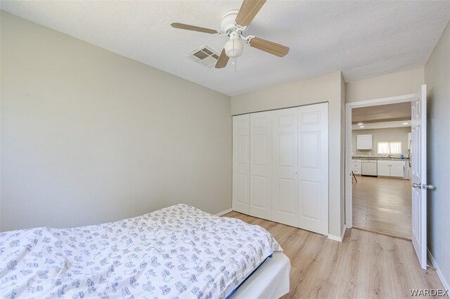 bedroom featuring light wood-style floors, baseboards, visible vents, and a closet