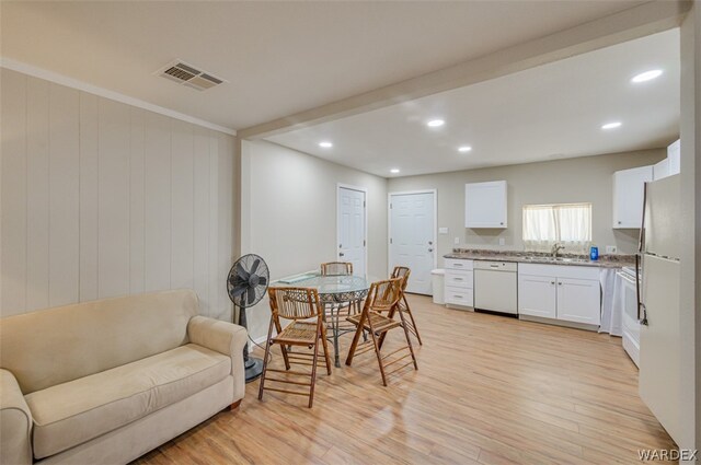 interior space with visible vents, white cabinets, dishwasher, open floor plan, and a sink