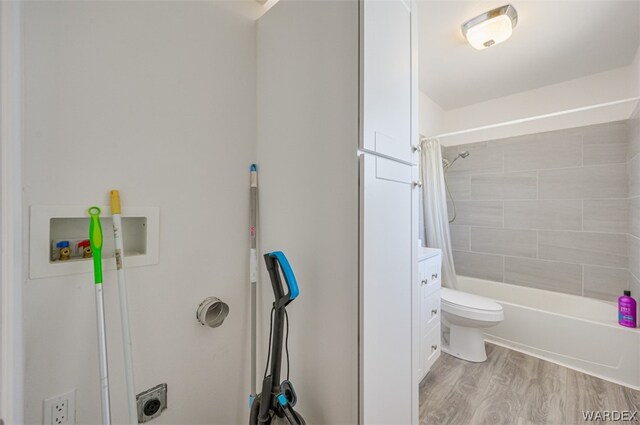 full bath featuring toilet, shower / bath combination with curtain, wood finished floors, and vanity