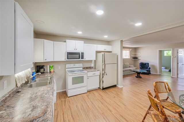 kitchen with light wood-style flooring, open floor plan, white cabinets, a sink, and white appliances