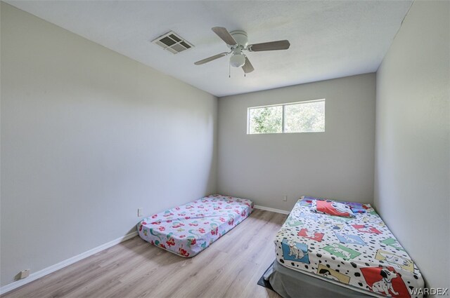 bedroom with light wood-style floors, baseboards, visible vents, and ceiling fan