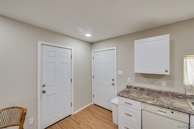 kitchen with baseboards, dark stone counters, white cabinets, white dishwasher, and light wood-type flooring