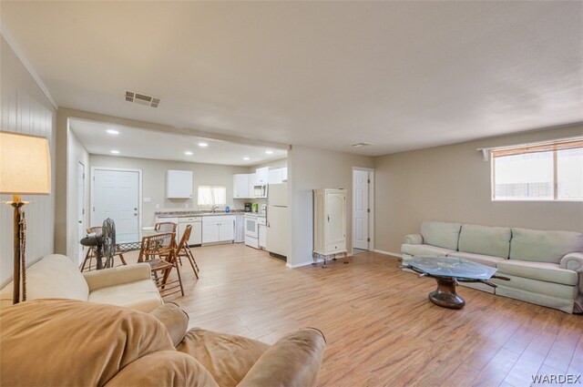 living area featuring a wealth of natural light, light wood-type flooring, visible vents, and recessed lighting