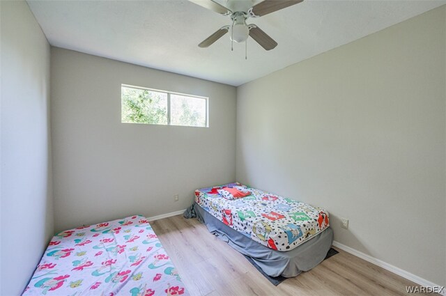 bedroom with light wood finished floors, ceiling fan, and baseboards