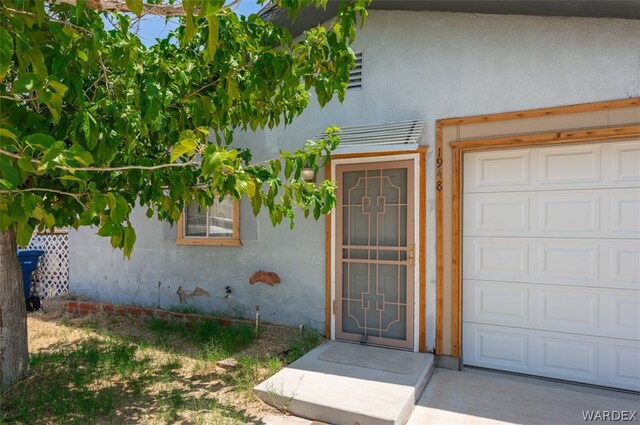 property entrance with a garage and stucco siding