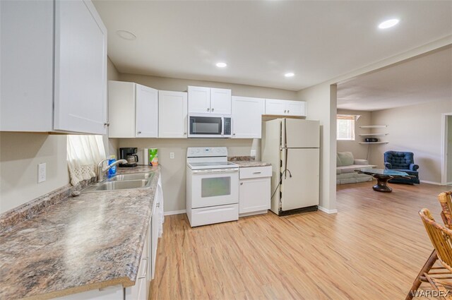 kitchen with light wood-style floors, white cabinets, a sink, white appliances, and baseboards