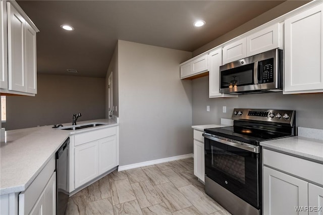 kitchen featuring stainless steel appliances, recessed lighting, white cabinets, a sink, and a peninsula