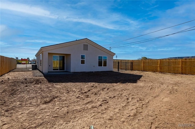 back of property with stucco siding, a fenced backyard, and central air condition unit