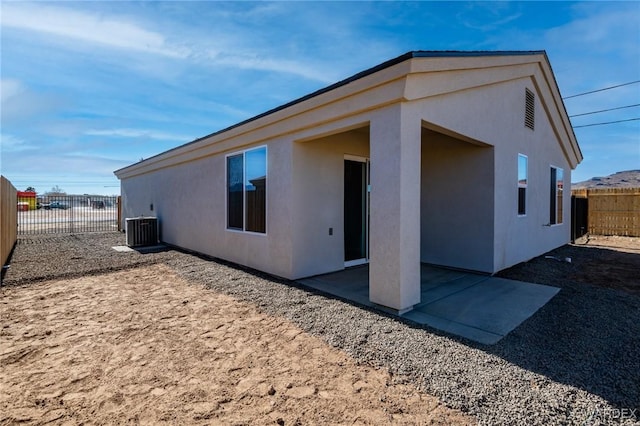 back of house featuring fence private yard, stucco siding, a patio area, and central AC unit