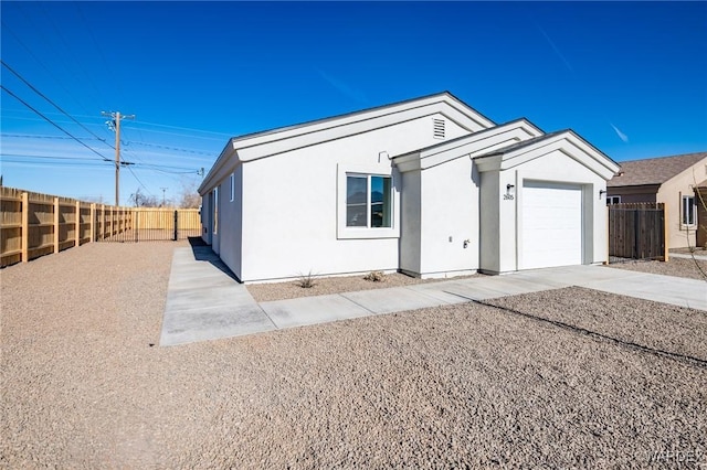 view of front facade with driveway, fence, an attached garage, and stucco siding