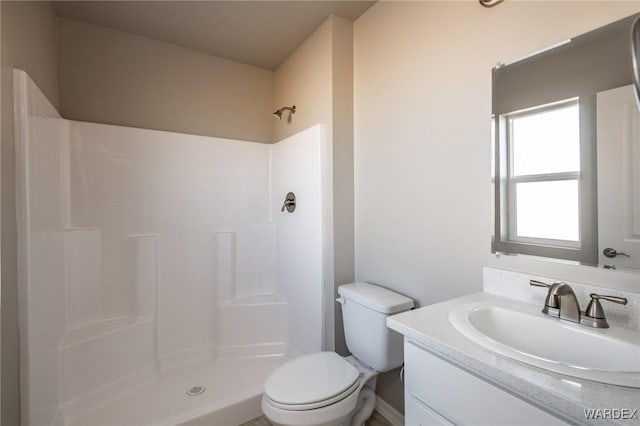 bathroom with a stall shower, vanity, and toilet