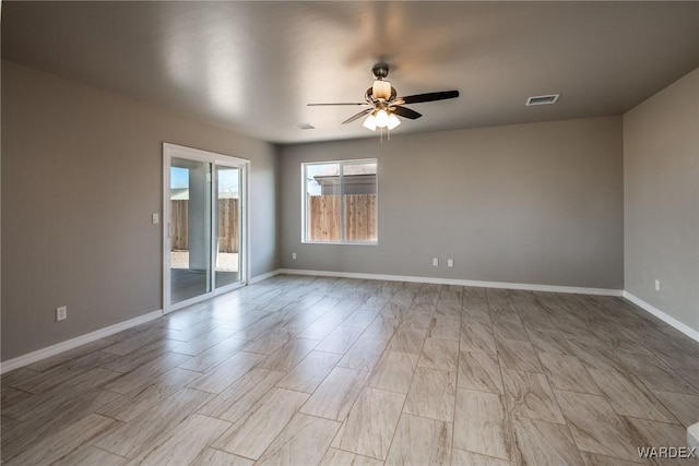 spare room featuring ceiling fan, visible vents, and baseboards