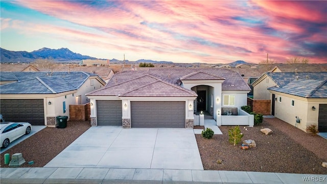 ranch-style home with driveway, an attached garage, a mountain view, and stucco siding