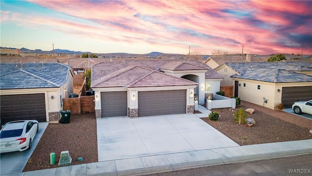 ranch-style house with stone siding, an attached garage, fence, and driveway