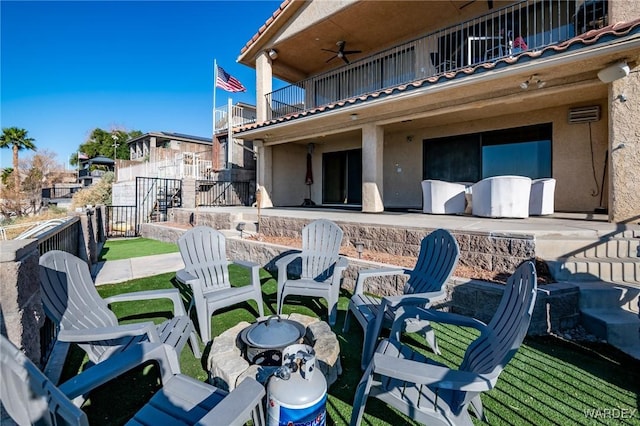 view of patio featuring ceiling fan, fence, and a balcony