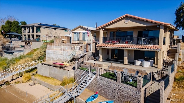 rear view of property with a balcony, ceiling fan, a tiled roof, a patio area, and stucco siding