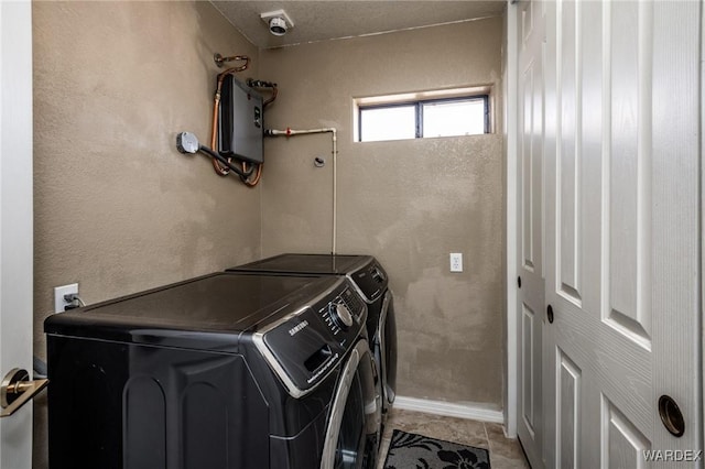 laundry room featuring light tile patterned floors, a textured wall, laundry area, washer and dryer, and water heater