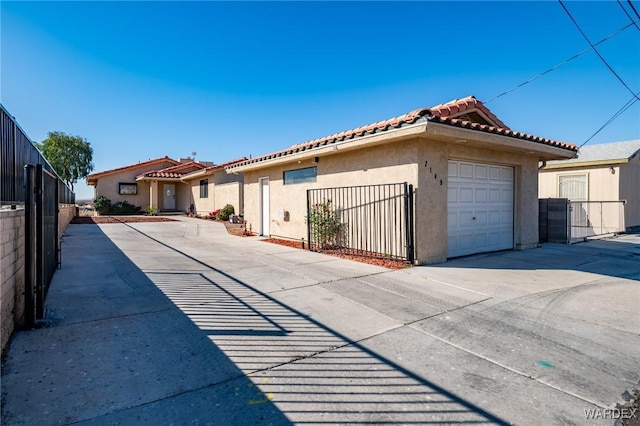 view of front of house featuring a garage, a tile roof, fence, concrete driveway, and stucco siding