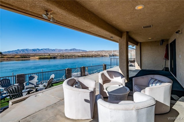 view of patio / terrace featuring a water and mountain view, visible vents, a balcony, and an outdoor hangout area