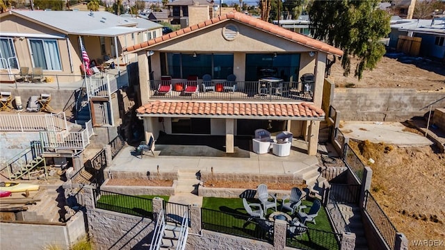 rear view of property featuring a balcony, a fenced backyard, a tile roof, a patio area, and stucco siding