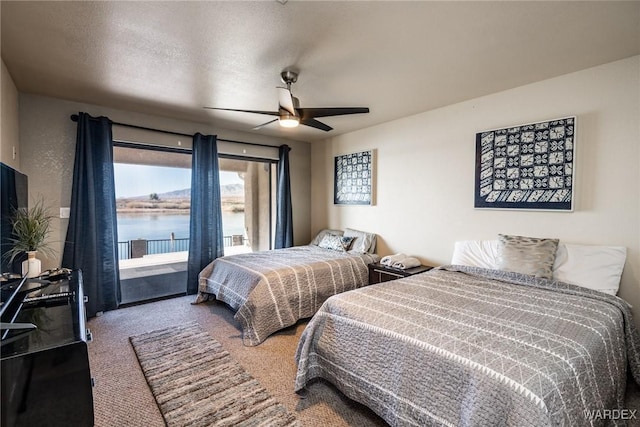 bedroom featuring a water view, a ceiling fan, carpet floors, and a textured ceiling