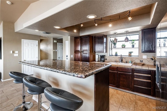 kitchen with a tray ceiling, a center island, a sink, and a breakfast bar area