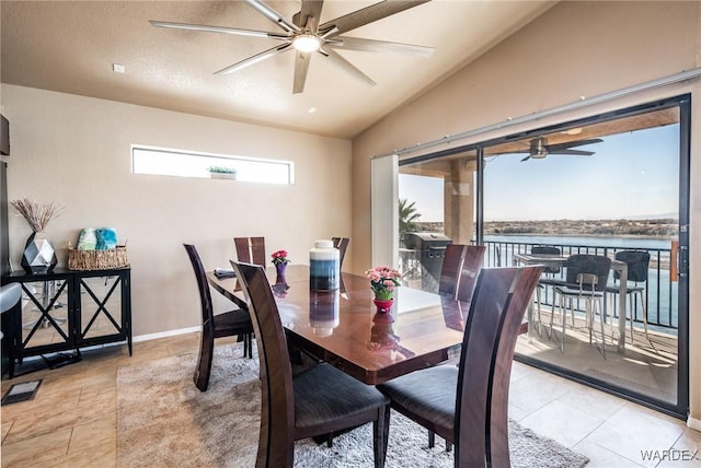 dining room featuring lofted ceiling, ceiling fan, light tile patterned floors, a water view, and baseboards