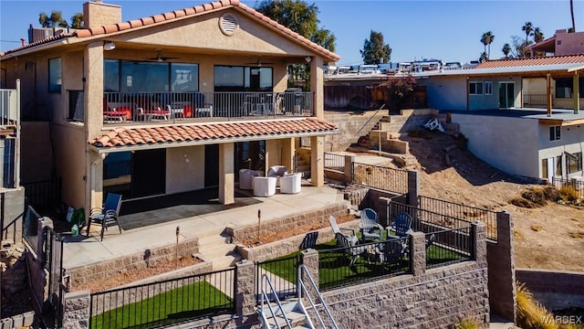 rear view of property featuring a patio, stucco siding, ceiling fan, a balcony, and fence