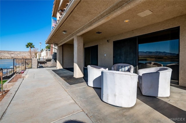 view of patio with a water view and fence