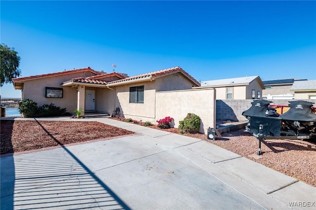 view of front of house featuring a tiled roof, fence, and stucco siding