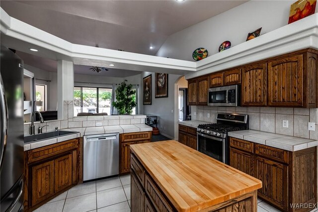 kitchen with stainless steel appliances, a kitchen island, decorative backsplash, and a sink