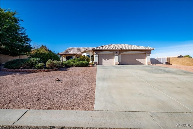 mediterranean / spanish-style house with stucco siding, concrete driveway, fence, a garage, and a tiled roof