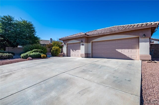 single story home with a garage, driveway, a tiled roof, and stucco siding